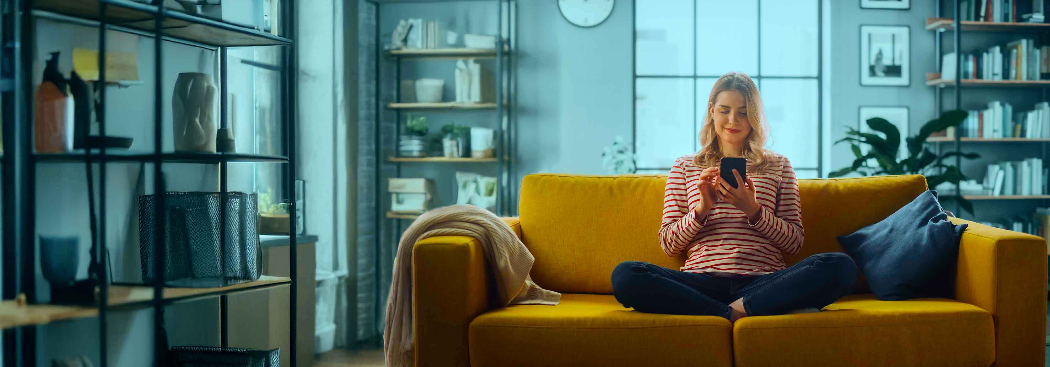 Female Using Smartphone in Stylish Living Room while Sitting on a Cozy
         Couch Sofa.